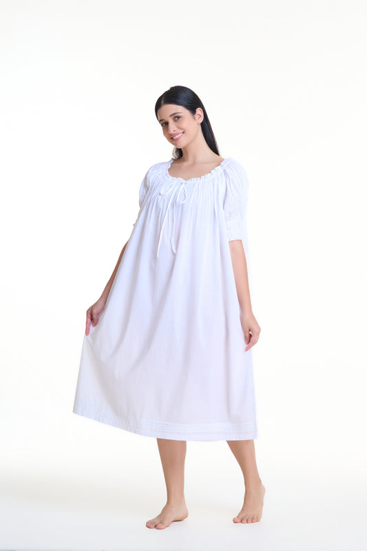 Short sleeved pin tucked white nightdress with puffed sleeves and front ribbon. This retro style cotton nightdress features delicate pleating, an empire waistline accentuating the bust and flowing out from there. Made of 100% cotton.