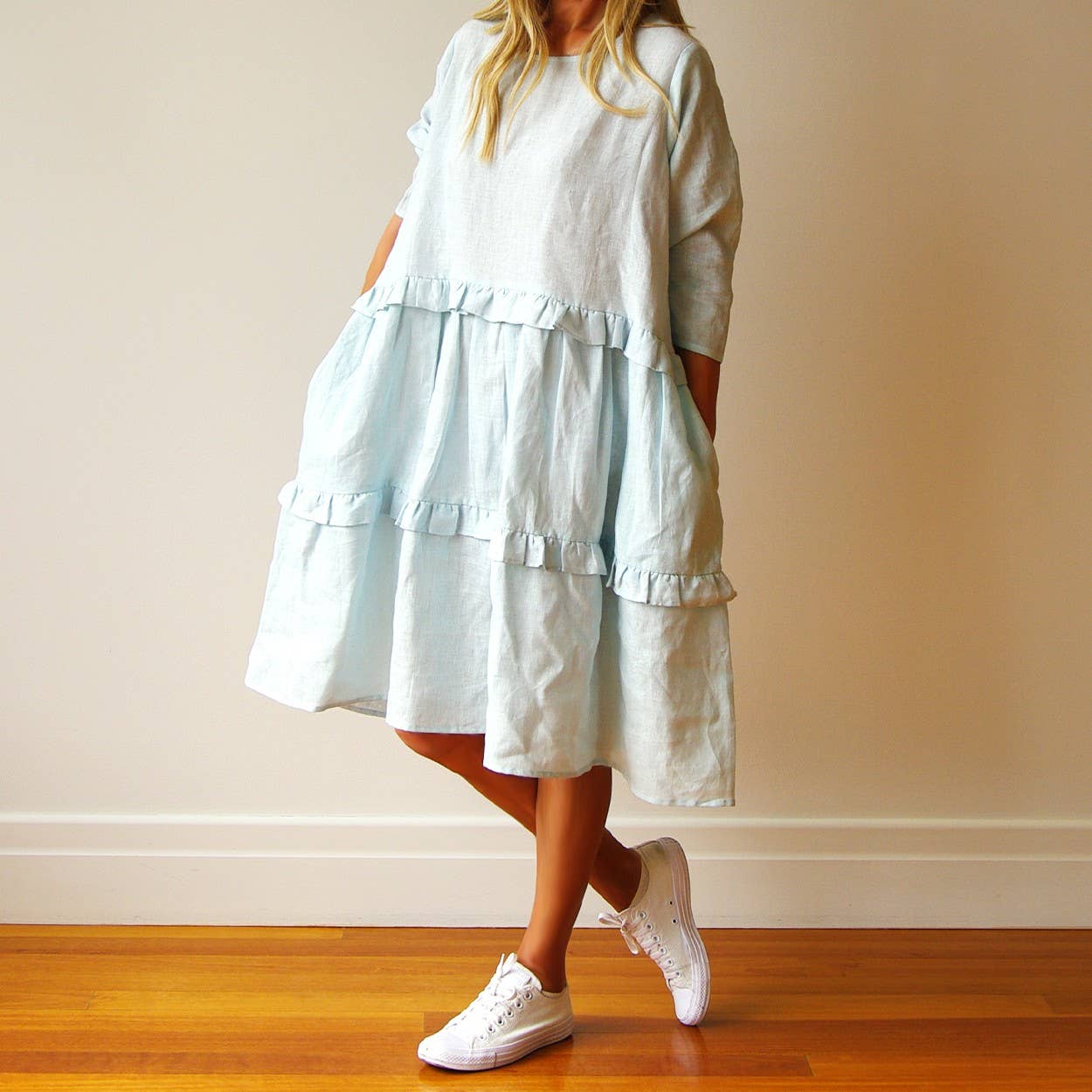 Light blue tiered dress worn by a person on a wooden floor with a plain wall background